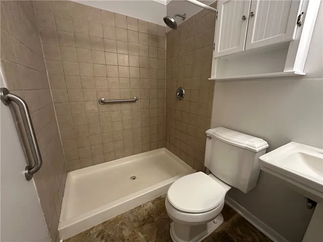 a white toilet sitting next to a bath tub and a shower