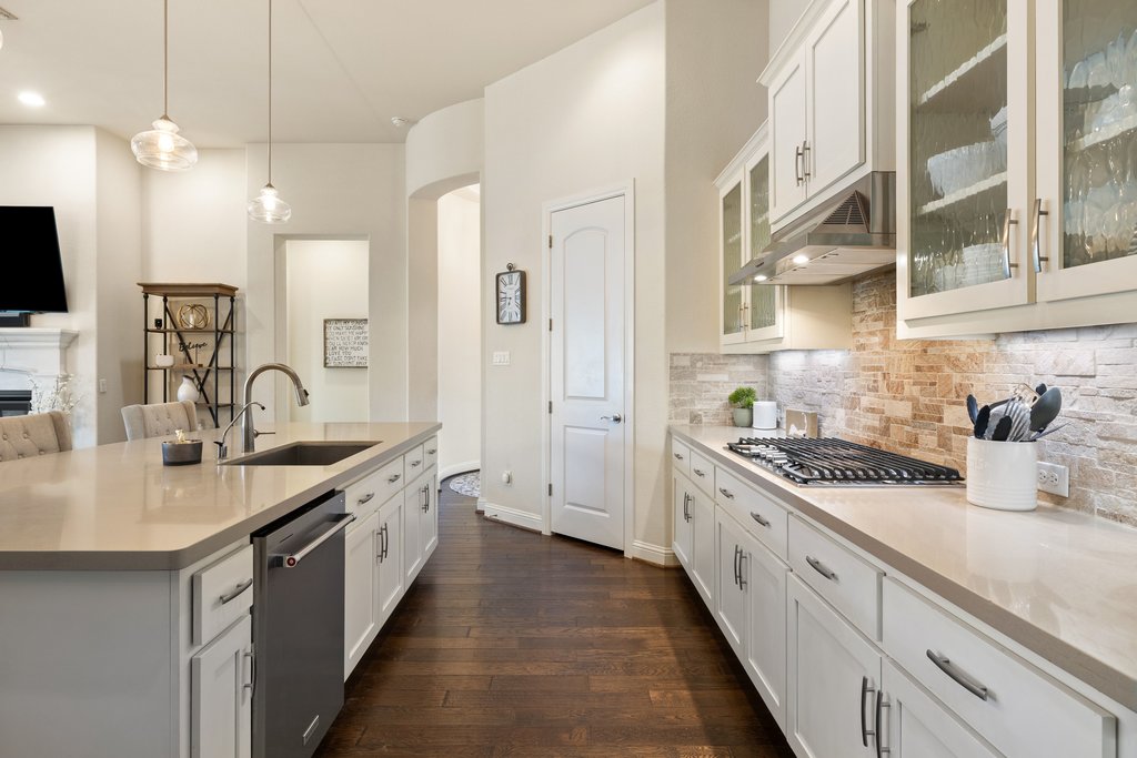 207 San Siro Cove Austin, TX 78738 - Photo 20 of 40 Kitchen features a built-in cooktop, stone accent backsplash, and KitchenAid appliances.
