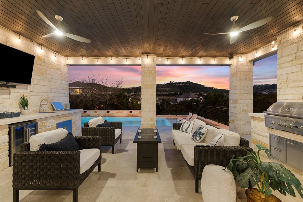 207 San Siro Cove Austin, TX 78738 - Photo 4 of 40 Enjoy gorgeous sunset views from one of several outdoor living spaces. The outdoor kitchen includes a built-in cooler, sink, fridge and wet towel hamper.