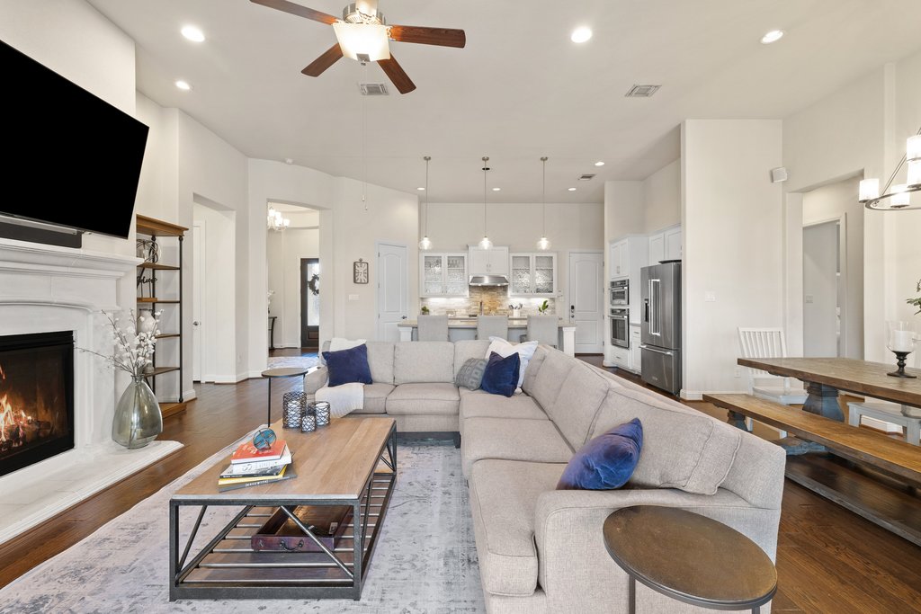 207 San Siro Cove Austin, TX 78738 - Photo 6 of 40 Expansive living area with wood floors, a gas log fireplace, recessed lighting, and high ceilings that enhances the open feel of the space.