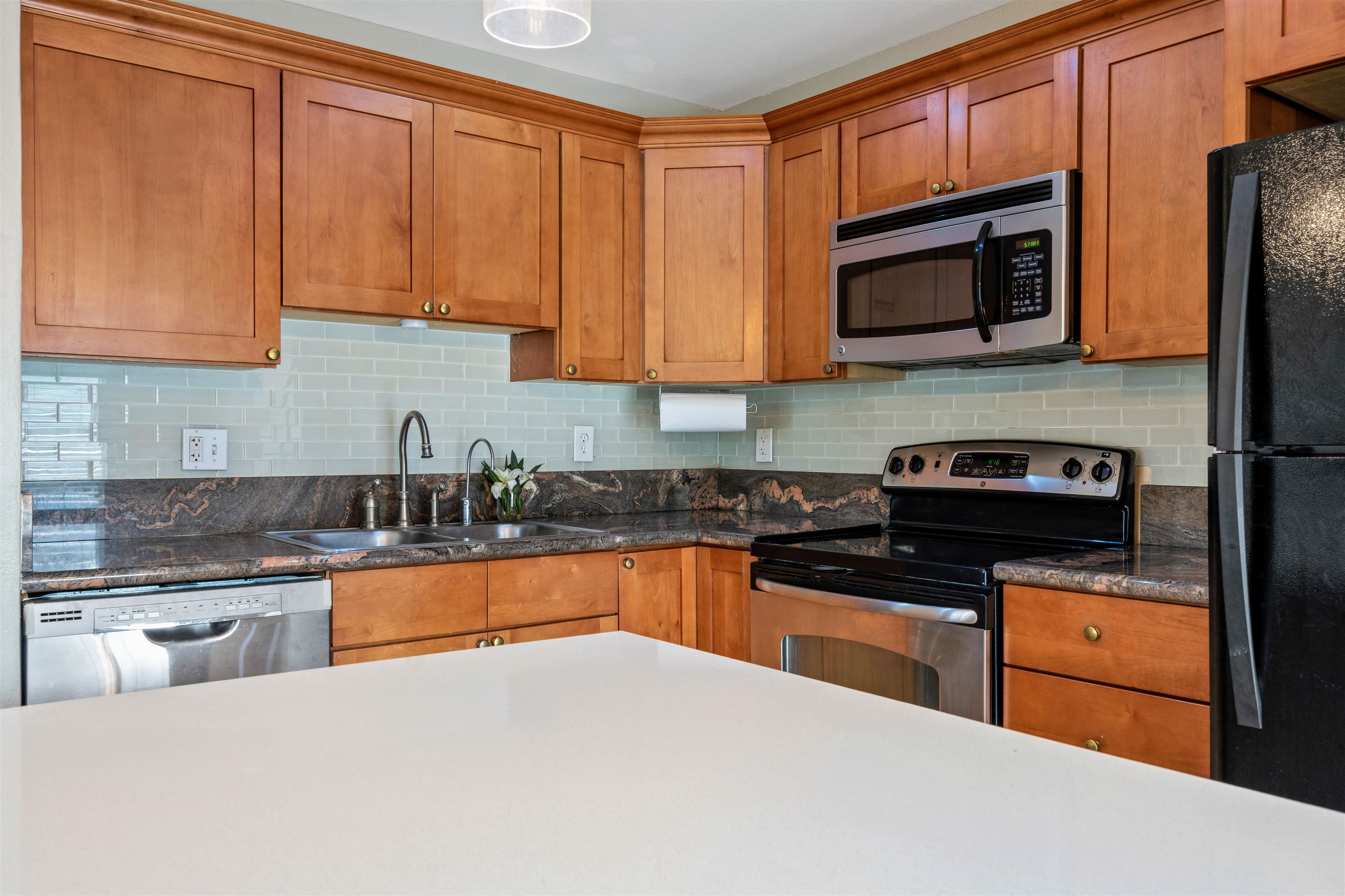 480 Kenolio Road, Unit 11206 Kihei, HI 96753 - Photo 2 of 31 a kitchen with stainless steel appliances granite countertop a stove a sink dishwasher and a microwave oven with white cabinets