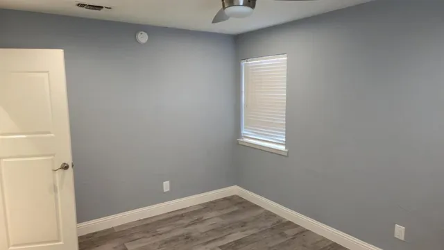 a view of an empty room with wooden floor and a window