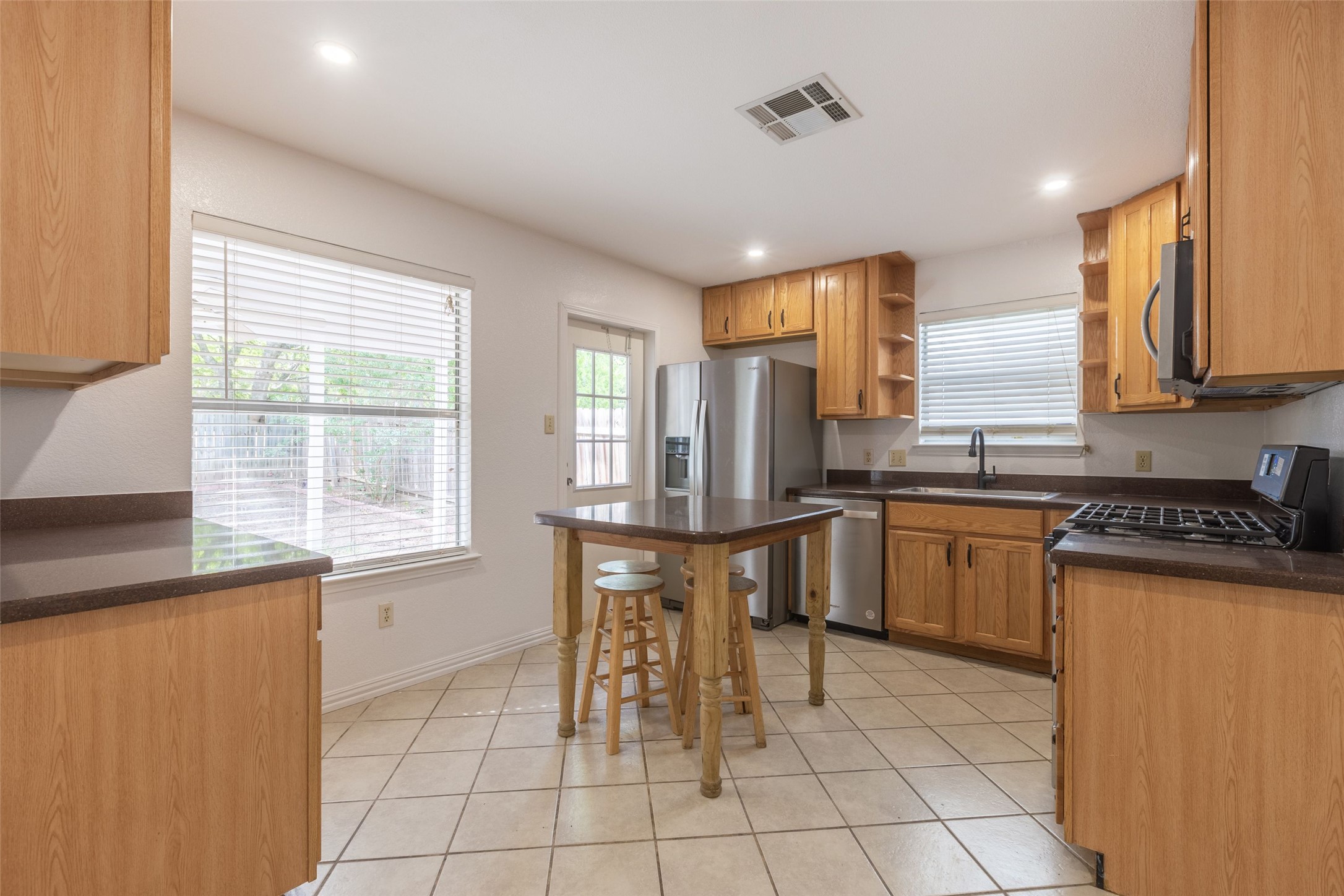 8506 Bisbee Court Austin, TX 78745 - Photo 6 of 20 Kitchen featuring warm wood cabinetry, dark countertops, stainless steel appliances, and tile flooring