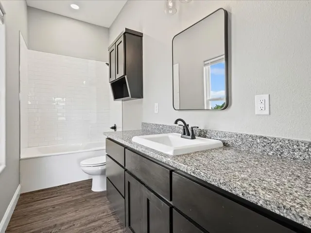 a bathroom with a granite countertop toilet sink and mirror