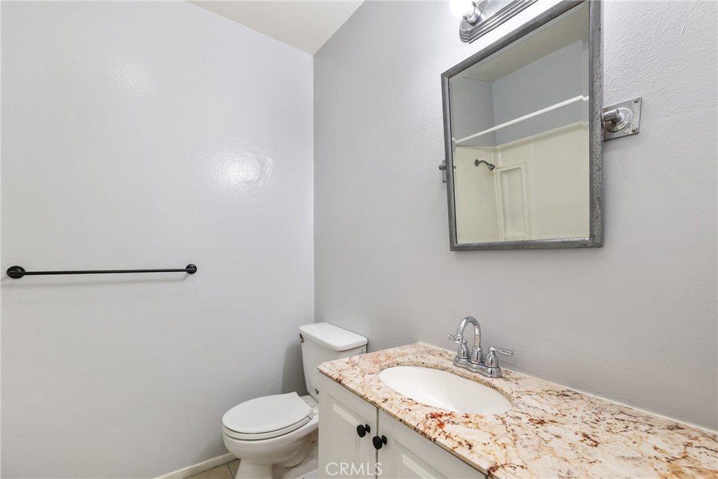 2521 West Sunflower Avenue, Unit R1 Santa Ana, CA 92704 - Photo 18 of 38 a bathroom with a granite countertop sink toilet and a mirror