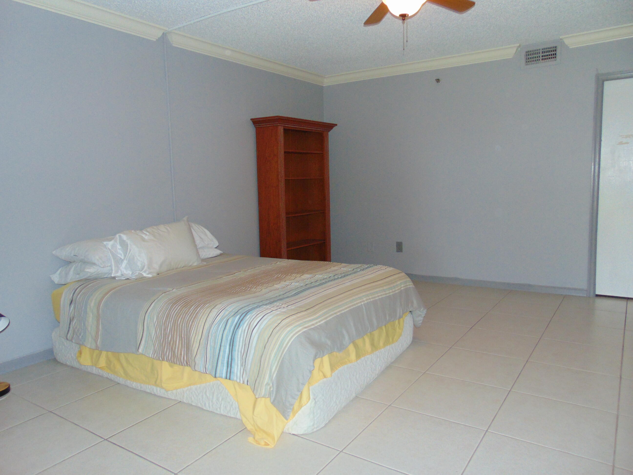 9220 Southwest 14th Street, Unit 3103 Boca Raton, FL 33428 - Photo 23 of 58 a bedroom with a bed and a chandelier fan