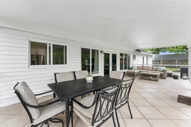 a view of a patio with table and chairs potted plants and a large tree