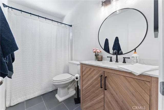 a bathroom with a sink a mirror a toilet and a window