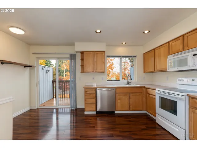 a open kitchen with granite countertop a stove top oven a sink dishwasher and white cabinets with wooden floor