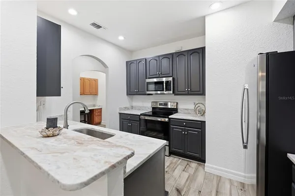 a kitchen with stainless steel appliances kitchen island granite countertop a refrigerator stove and sink