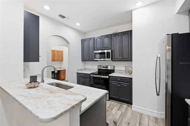 a kitchen with stainless steel appliances kitchen island granite countertop a refrigerator stove and sink