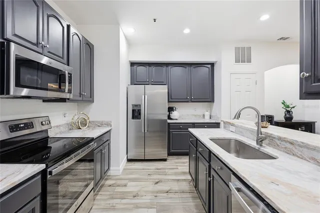 a kitchen with granite countertop a sink stainless steel appliances and cabinets