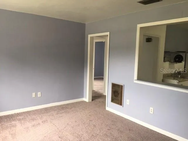 a view of an empty room with window and bathroom