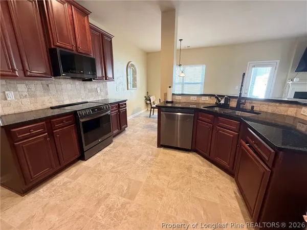 a kitchen with stainless steel appliances granite countertop wooden cabinets a stove top oven a sink and dishwasher