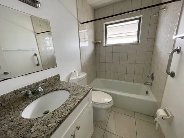 a bathroom with a granite countertop sink a toilet a mirror a bathtub and shower