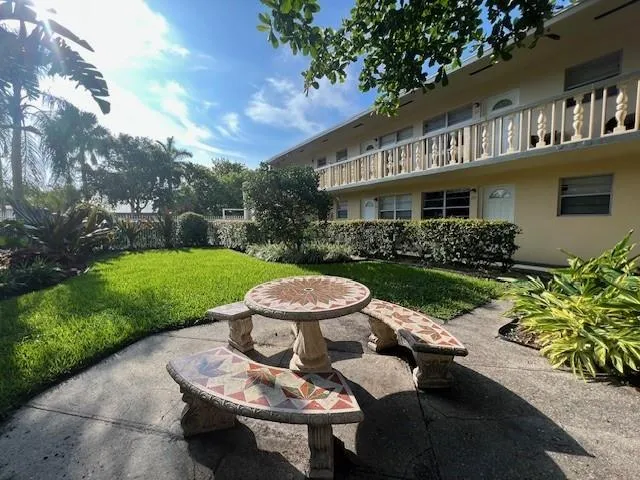 a view of a patio with table and chairs potted plants and large tree