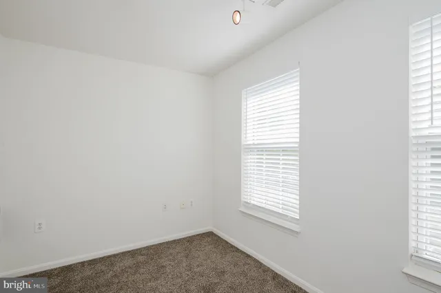 a view of an empty room with wooden floor fireplace and a window