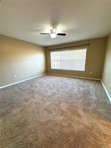 en empty room with windows and chandelier fan