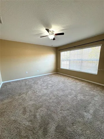 an empty room with chandelier fan and windows