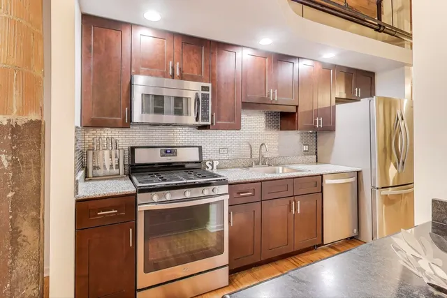 a kitchen with stainless steel appliances granite countertop a sink stove and cabinets