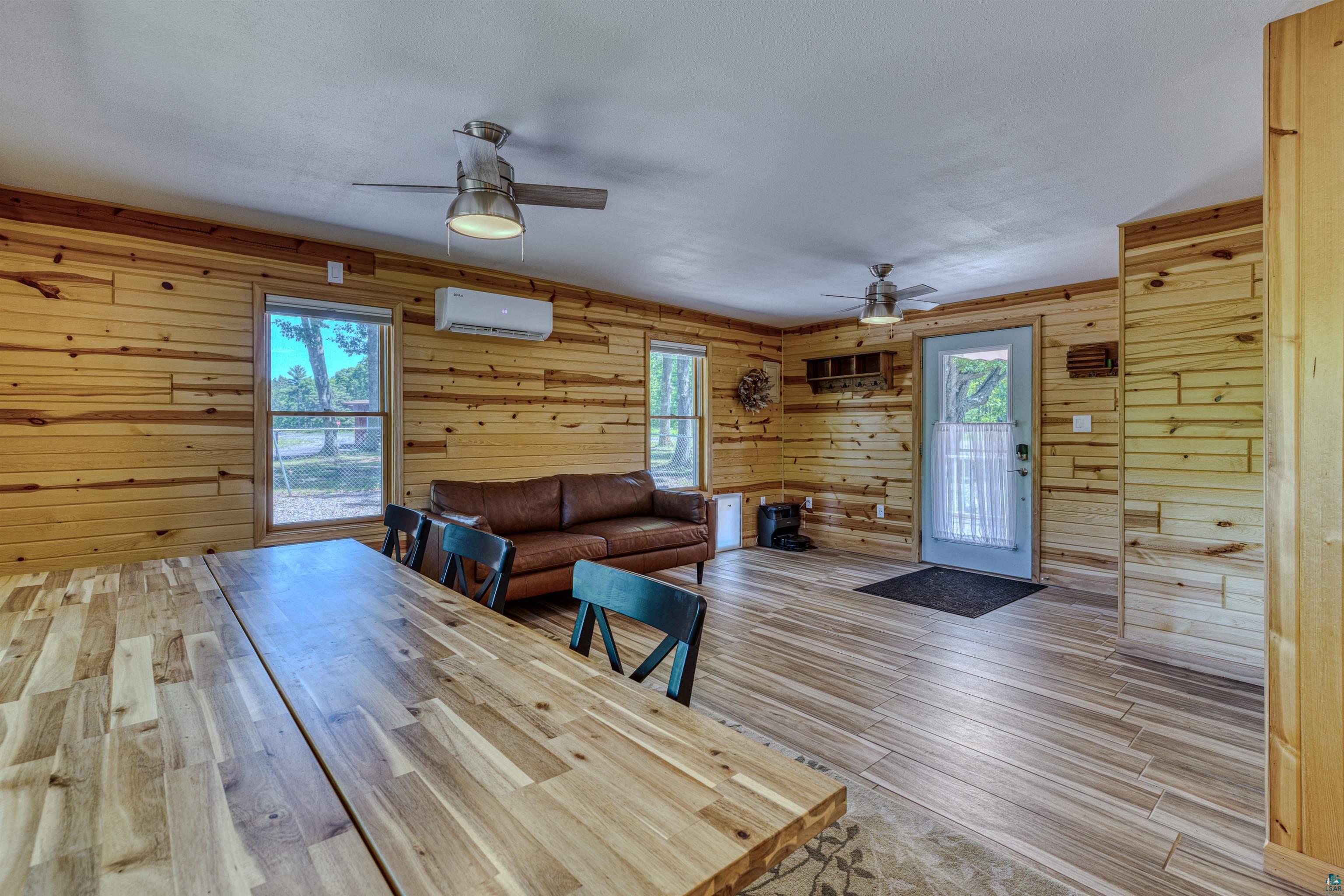 66075 Rooster Road Iron River, WI 54847 - Photo 21 of 52 Open-concept interior featuring wood-finish wall paneling, wood-finish flooring, multiple windows, and ceiling fans