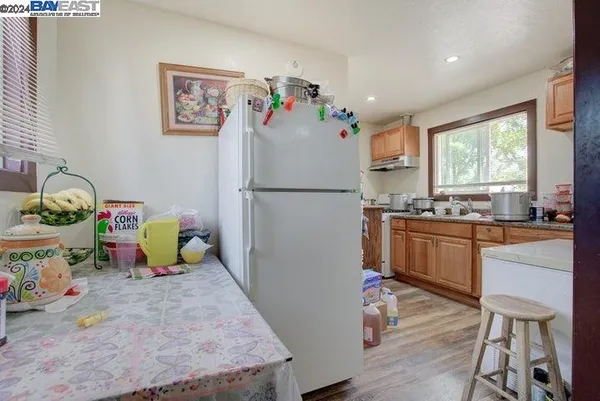 a white kitchen with a refrigerator a stove top oven a sink and a window