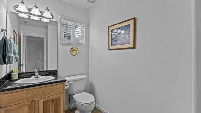 a bathroom with a granite countertop toilet sink and mirror
