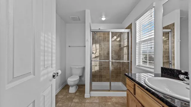 a bathroom with a granite countertop sink a toilet a mirror and shower