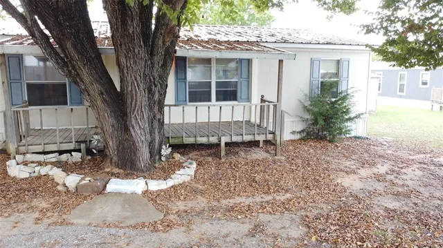 a view of a house with a yard and large tree