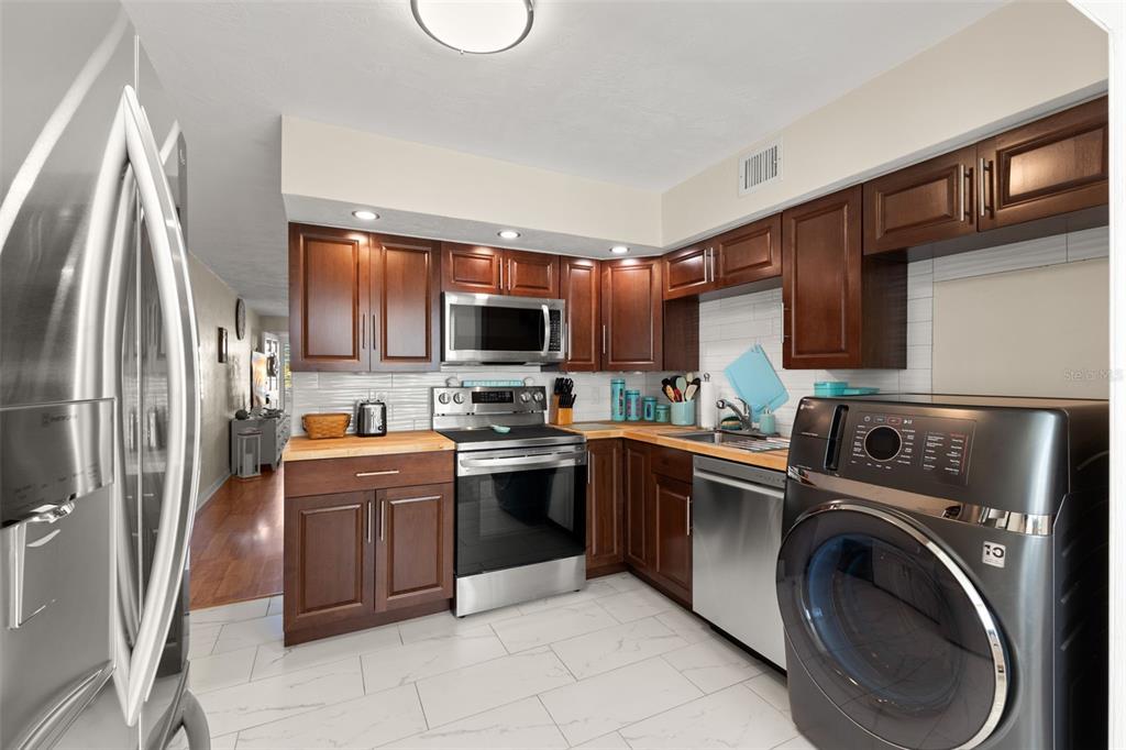 2461 Canadian Way, Unit 27 Clearwater, FL 33763 - Photo 11 of 35 a kitchen with stainless steel appliances granite countertop a refrigerator sink and stove top oven