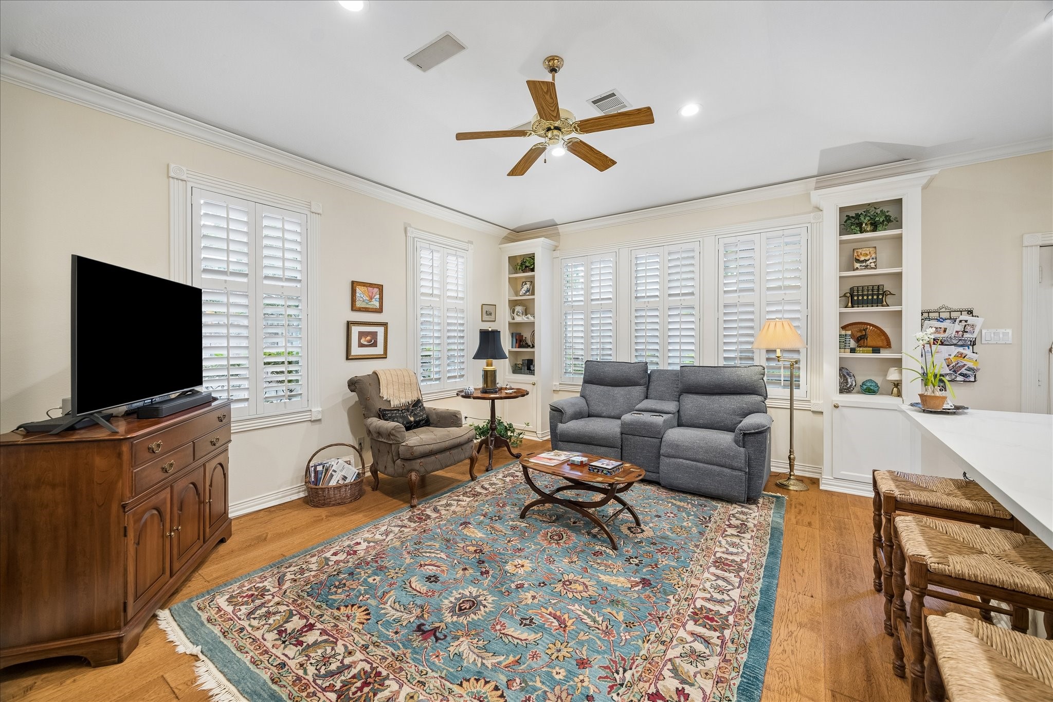 6611 Trebeck Lane Spring, TX 77379 - Photo 13 of 33 Warm and inviting family room featuring custom built-ins, plantation shutters, and abundant natural light, ideal for relaxed living.