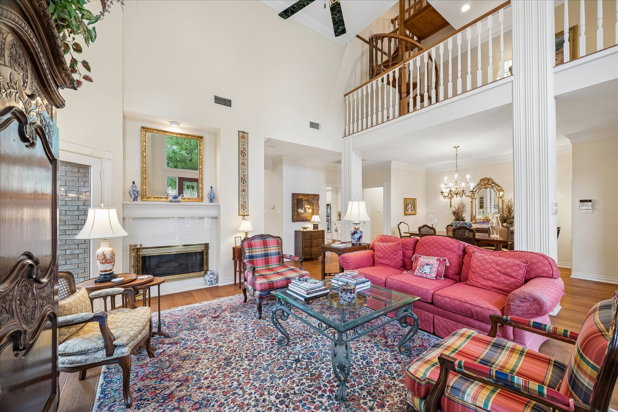 6611 Trebeck Lane Spring, TX 77379 - Photo 6 of 33 Light-filled living room with soaring ceilings, rich wood flooring, and a cozy fireplace, creating an inviting space for both everyday living and entertaining.