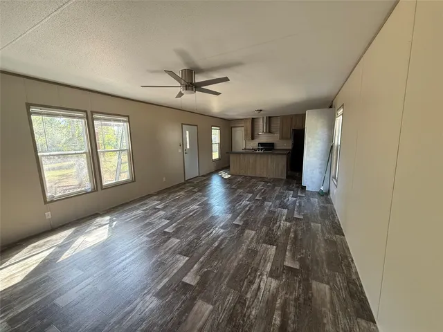 a view of a big room with wooden floor a ceiling fan and windows