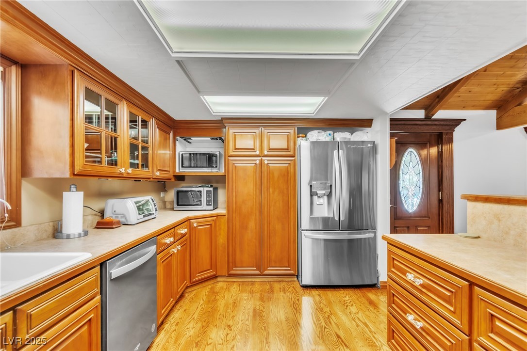 4063 Zugspitz Way Las Vegas, NV 89124 - Photo 55 of 86 Kitchen with stainless steel appliances, light countertops, light wood finished floors, glass insert cabinets, and brown cabinetry