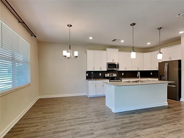 a kitchen with stainless steel appliances granite countertop a sink a refrigerator a stove a microwave and a wooden floors