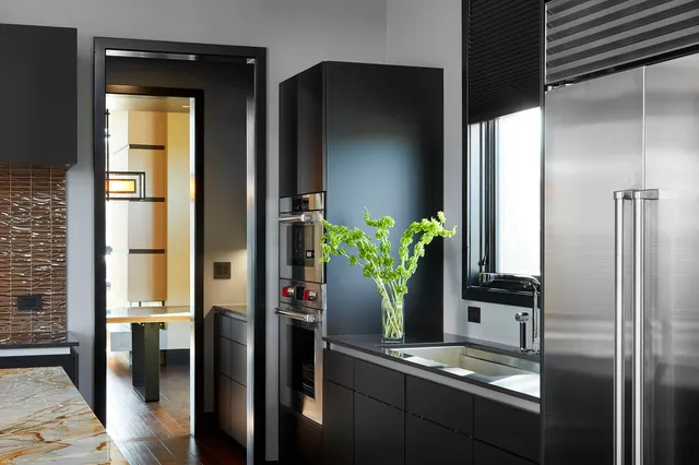 a kitchen with stainless steel appliances granite countertop a refrigerator a sink dishwasher a stove and a dining table with wooden floor