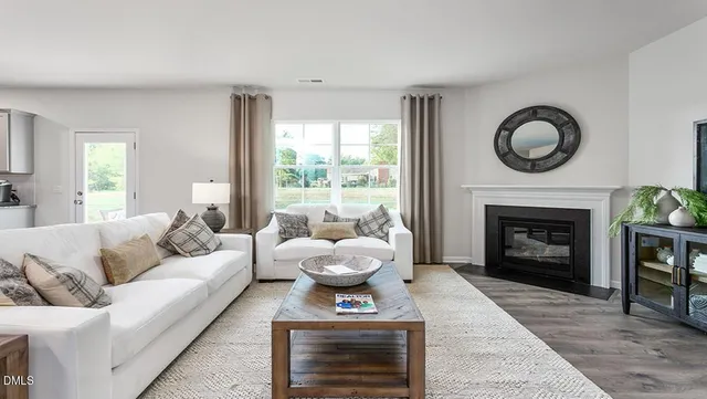 a living room with furniture a fireplace a flat screen tv and a large window