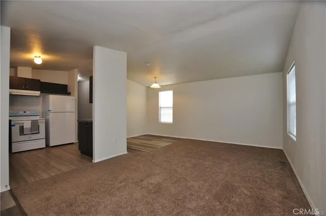 a view of empty room with kitchen and window