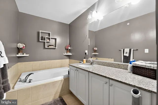 a bathroom with a granite countertop bathtub a double vanity sink and mirror