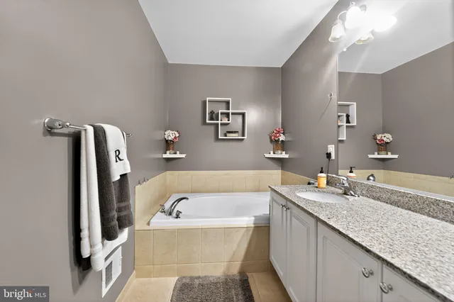 a bathroom with a granite countertop tub sink and mirror