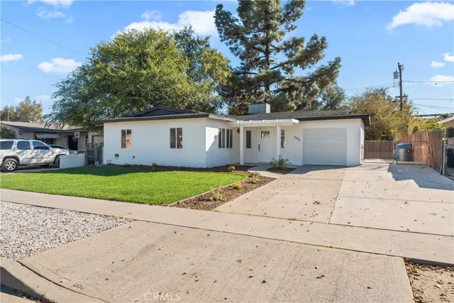 a view of a white house with a small yard and large trees