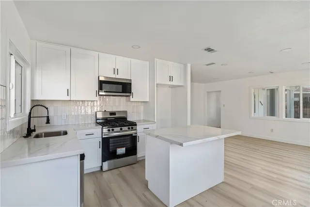 a kitchen with white cabinets stainless steel appliances and wooden floor