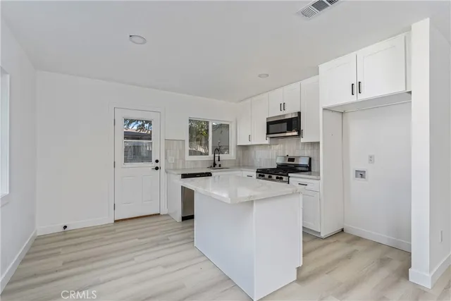 a kitchen with stainless steel appliances a stove top oven a refrigerator a sink dishwasher and a refrigerator with wooden floor