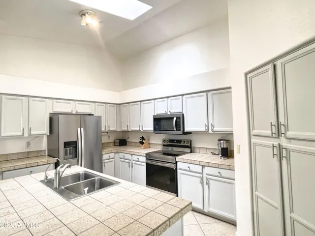a kitchen with a sink a stove and white cabinets