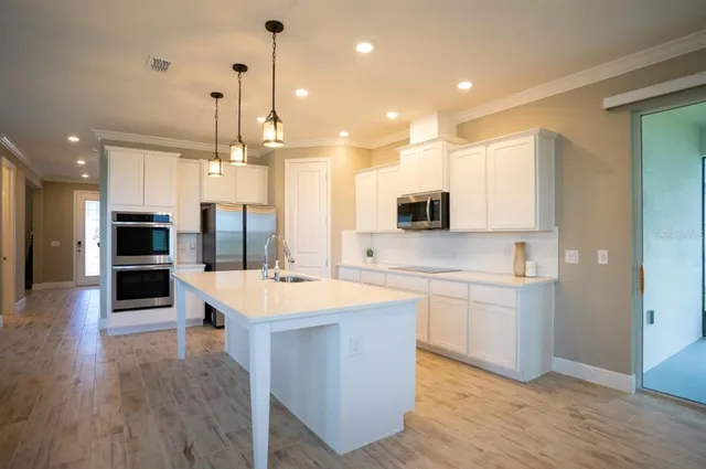 a large kitchen with kitchen island a sink a stove a oven a dining table and chairs