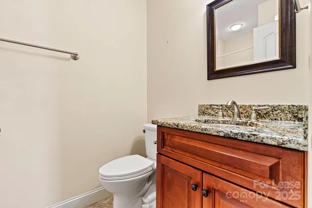 a bathroom with a granite countertop toilet and a sink