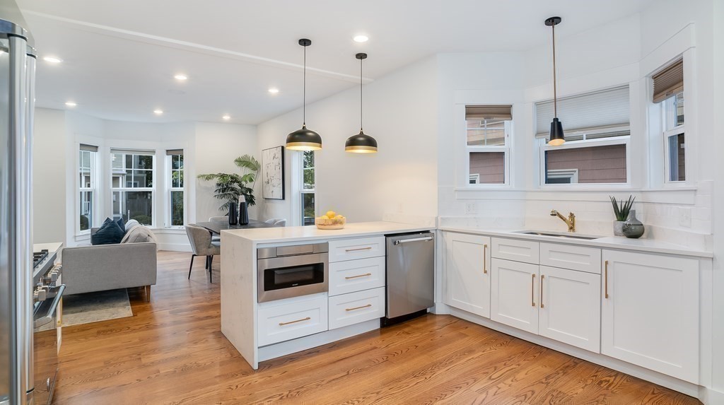 38 Chester Street, Unit 1 Somerville, MA 02144 - Photo 9 of 32 a kitchen with stainless steel appliances granite countertop a stove a sink and white cabinets