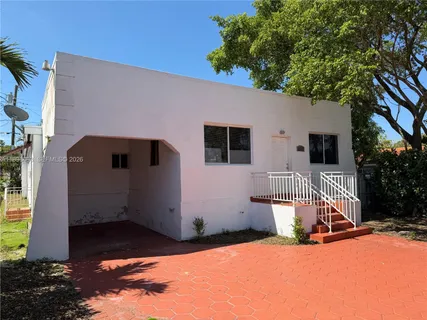 a front view of house with yard outdoor seating and covered with trees