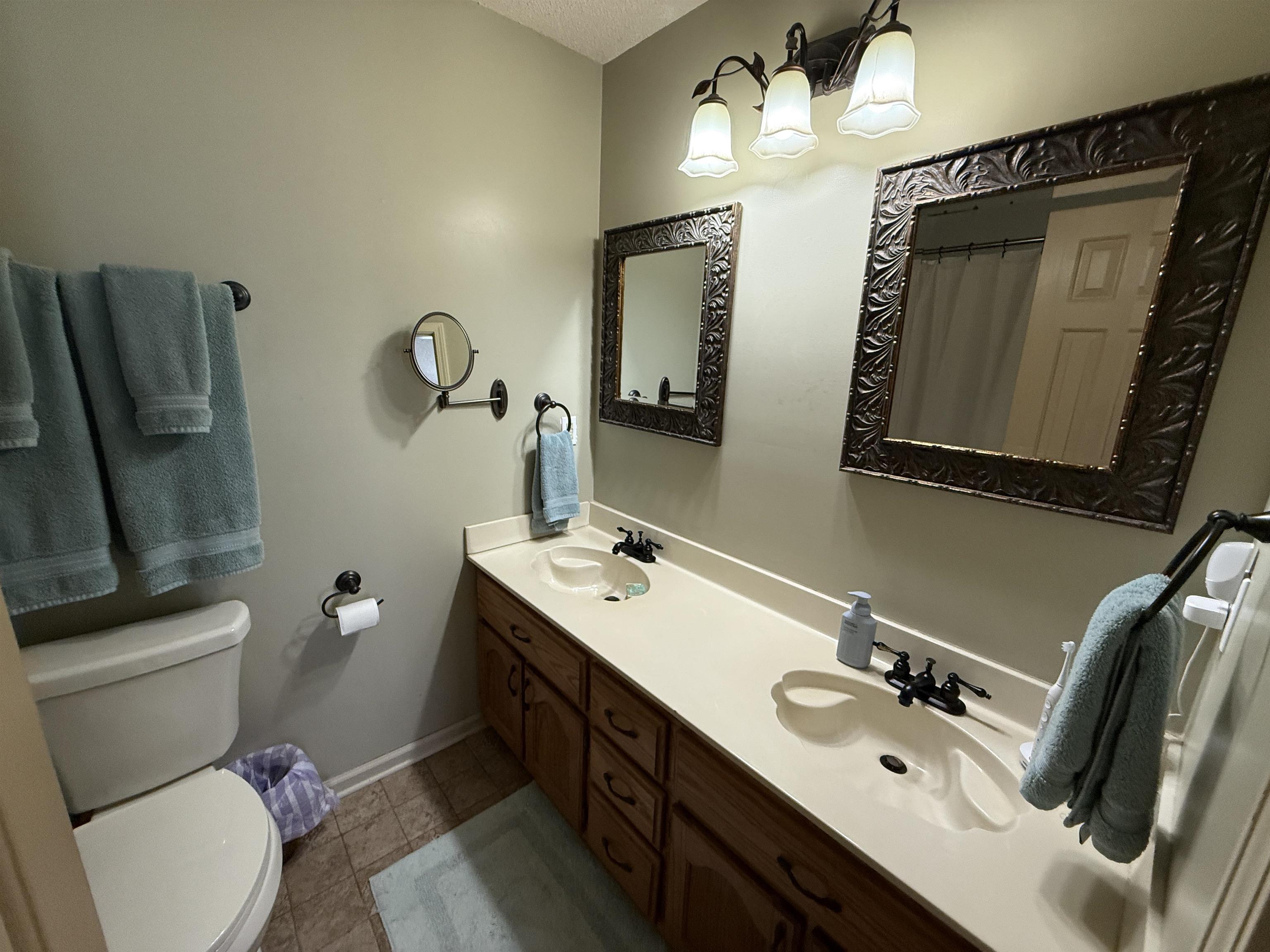 185 Mignon Road Atoka, TN 38004 - Photo 23 of 34 Double vanity with integrated sinks, rich wood cabinetry, coordinating framed mirrors, and a three-light fixture overhead