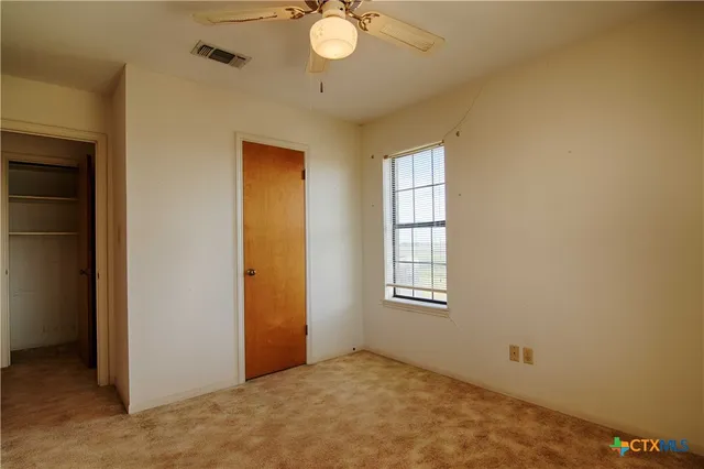 an empty room with windows and fan
